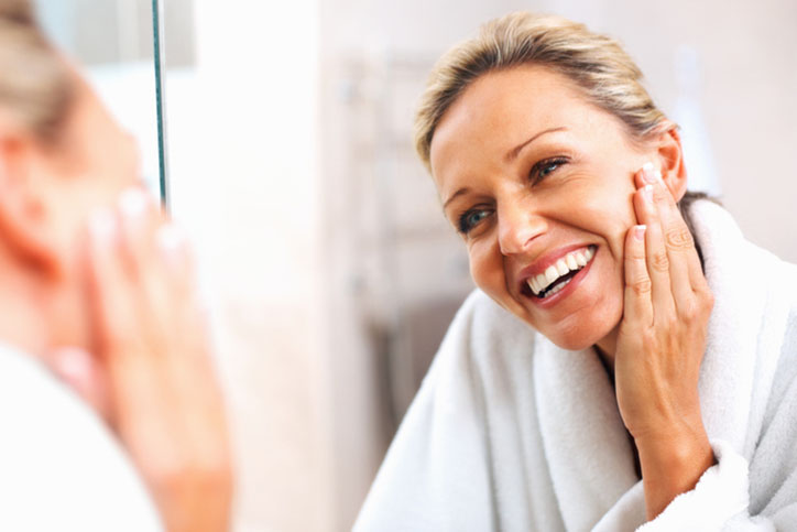 Happy mature woman admiring herself in the mirror Dermabrasion in Savannah, GA